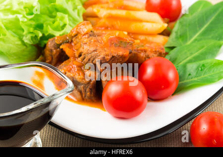 Voir Gros plan sur un repas de ragoût de boeuf avec des pâtes penne, tomates cerise et d'herbes fraîches avec une faible profondeur de foyer Banque D'Images