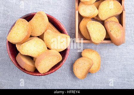 Morceaux de rusk dans le vieux brown bol en bois sur une nappe gris de jute. Top View close-up. Banque D'Images