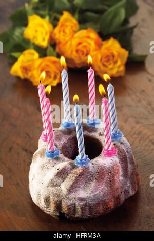 Des bougies sur un gâteau bundt, roses jaune Banque D'Images