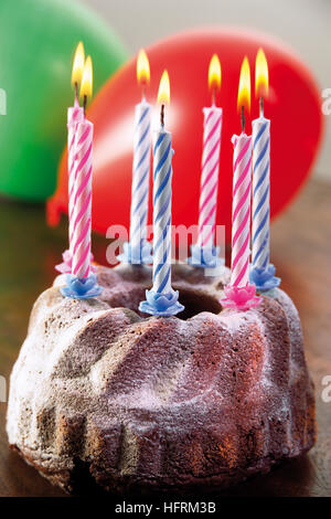 Des bougies sur un gâteau bundt, ballons Banque D'Images