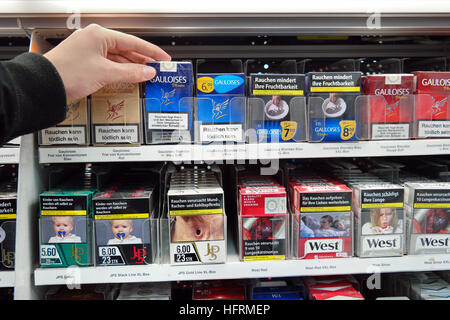 Des cigarettes dans un supermarché avec photos sur les paquets de cigarettes pour illustrer les dangers du tabagisme Banque D'Images