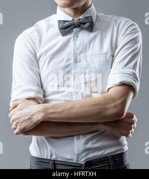 L'homme dans une chemise blanche avec rayures gris papillon sur un cou. Image main d'hommes croisés Banque D'Images