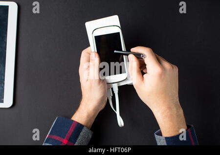 L'homme à l'aide d'un téléphone portable blanc connecté à une banque d'alimentation Banque D'Images