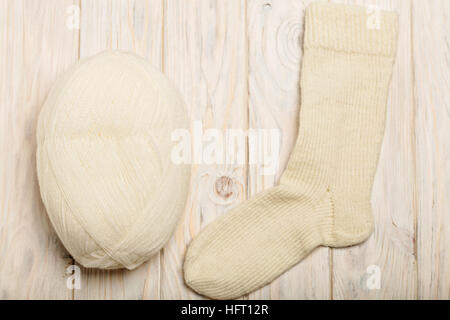 Fil blanc chaussettes tricotées et de lumière sur fond de bois. Banque D'Images