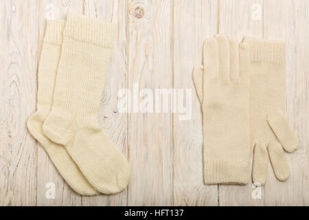 À partir d'un tricot de fils blanc et gants chaussettes sur un fond en bois clair. Banque D'Images