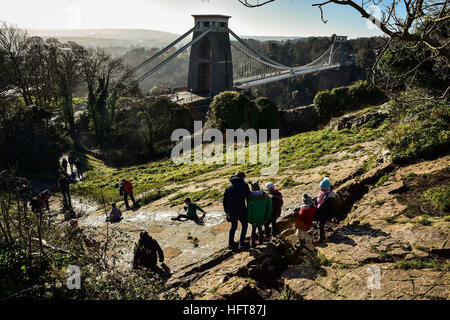 Les enfants glissent sur une diapositive de roche naturelle, qui a été créé par des générations d'enfants glissant sur la pente de calcaire près de Clifton Suspension Bridge sur Clifton Downs, Bristol, en tant que parties du Royaume-Uni seront saisis par la glace comme une vague de froid commence en 2017. Banque D'Images