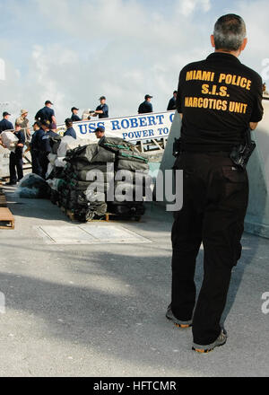 070105-N-5240C-011 Key West, Floride (janv. 5, 2007) - Un officier avec MiamiÕs La Section des enquêtes spéciales de l'unité des stupéfiants regarde sur comme marins affectés à la frégate lance-missiles USS Robert G. Bradley (FFG 49), garde de la côte, et les agents de la Drug Enforcement Agency décharger neuf tonnes de cocaïne sur une jetée à la base aéronavale de Key West. Bradley faisait partie d'un effort national et interagences pour interdire la circulation des stupéfiants aux États-Unis. U.S. Navy photo by Mass Communication Specialist 2e classe Timothy Cox (libéré) US Navy 070105-N-5240C-011 un officier avec Miami  % %5Ersquo,s Banque D'Images