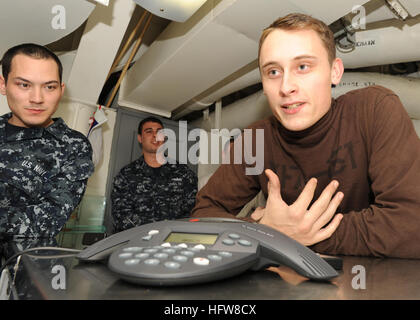 Aéronautique mécanicien structurel Airman Apprentice à bord de l'USS Abraham Lincoln (CVN 72) parle avec le gardien des Boston Bruins Tim Thomas par téléphone lors du déploiement dans la zone de responsabilité de la 5e flotte américaine, dans le cadre d'activités de sensibilisation avec des personnalités sportives de premier plan. Banque D'Images