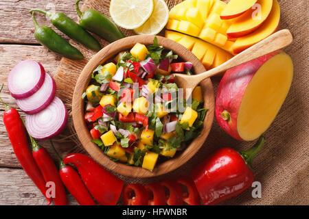 La Salsa à la mangue, la coriandre, les oignons et poivrons, Close up dans un bol et les ingrédients sur la table. Vue du dessus horizontale Banque D'Images