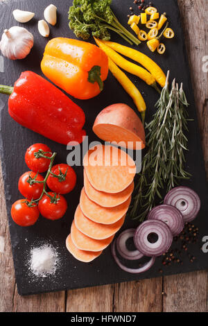 Ingrédients : légumes patates douces, poivrons, tomates, oignons, ail, romarin et d'épices sur une liste de sélection. vertical Vue de dessus Banque D'Images