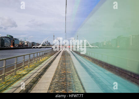 Samuel Beckett bridge sur la Liffey vu en miroir dans un verre coloré mur d'un bâtiment sur North Wall Quay, Dublin, Irlande Banque D'Images