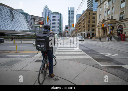 TORONTO, CANADA - 31 décembre 2016 : Uber mange delivery man sur une bicyclette en attente de traverser une rue Banque D'Images