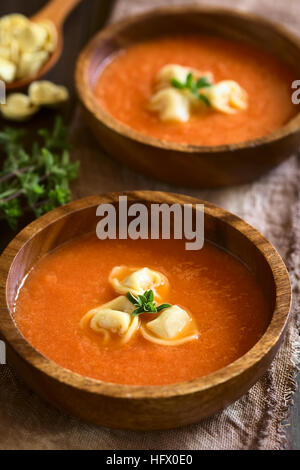 Crème fraîche maison de soupe aux tomates avec tortellini garnies d'origan frais, servis dans des bols en bois Banque D'Images