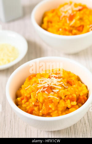 Risotto de carottes fraîches faites maison avec purée de carotte et carotte rôti pièces, garnie de fromage râpé Banque D'Images