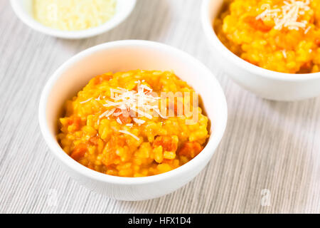 Risotto de carottes fraîches faites maison avec purée de carotte et carotte rôti pièces, garnie de fromage râpé Banque D'Images