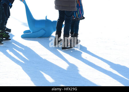 Plaisir en famille sur la patinoire de plein air pour enfants, apprendre à patiner avec joint en plastique comme des aides à la formation Banque D'Images
