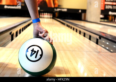 Femme main tenant une boule de bowling dans la main sur l'allée brailler Banque D'Images