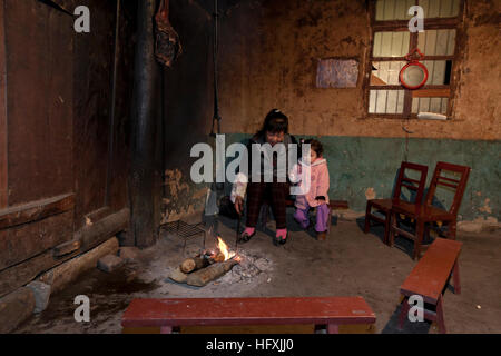 Un bambin pendant un week-end avec sa famille sur les montagnes est situé sur l'hôte autour du feu dans le salon d'une maison de ferme dans un endroit éloigné Banque D'Images