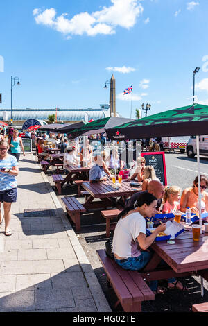 Front de l'Anglais à Ramsgate avec des gens assis à des tables et des chaises à l'ombre des parasols, profitant des boissons et de la nourriture par temps chaud en été. Banque D'Images