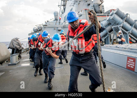 Eaux à l'EST DU JAPON (nov. 5, 2016) marins affectés à l'avant-déployés de la classe Arleigh Burke destroyer lance-missiles USS Barry (DDG 52) une ligne sur la partie arrière du pont de missiles au cours d'un ravitaillement en mer avec la commande de transport maritime militaire (MSC) de marchandises et de munitions Ship USNS Charles Drew (T-AKE 10) comme une partie de l'épée 17 Keen (KS17). KS17 est une bi, chef de l'état-major interarmées-dirigé, AMÉRICAINES DU PACIFIQUE-parrainé Terrain (FTX). KS17 est conçu pour répondre aux objectifs de défense mutuelle en augmentant la préparation au combat et l'interopérabilité entre le Japon Self-Defens Banque D'Images