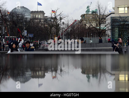 Berlin, Allemagne. 2 Jan, 2017. La porte de Brandebourg (r) et le bâtiment du Reichstag reflètent dans une flaque d'eau sur une stèle à l'Holocaust Memorial à Berlin, Allemagne, 2 janvier 2017. Photo : Maurizio Gambarini/dpa/Alamy Live News Banque D'Images