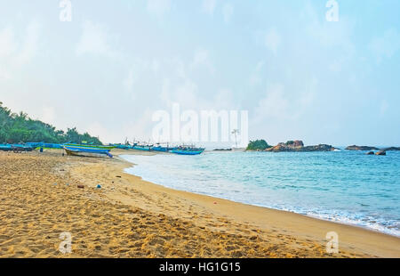 La pittoresque plage de sable avec les petits îles rocheuses et des bateaux de pêche à Hikkaduwa, Sri Lanka. Banque D'Images