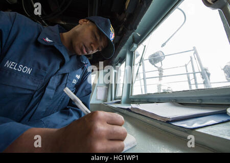 Maître de Manœuvre de la Marine américaine Kehmal 3e classe Nelson fait une entrée de journal de pont dans le pilothouse à bord du destroyer lance-missiles USS Ramage (DDG 61) dans la mer Méditerranée le 5 décembre 2013, lorsque le bateau quitte la baie de Souda, la Grèce. Le Ramage déployés pour appuyer les opérations de sécurité maritime et les efforts de coopération en matière de sécurité dans le théâtre américain dans la zone de responsabilité de la sixième flotte. (U.S. Photo par marine Spécialiste de la communication de masse Jackie 3e classe/Hart) Parution USS Ramage operations 131205-N-VC236-027 Banque D'Images