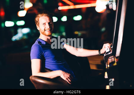 Beau jeune homme avec machine à sous dans le casino Banque D'Images