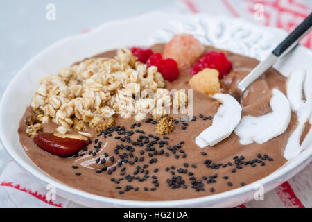 Smoothie chocolat bol de gruau, graines de sésame et de framboises pour le petit-déjeuner. L'amour pour la santé de l'aliment cru concept. Banque D'Images