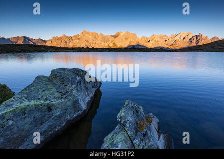 Rochers au lac Laramon. Lumière du soleil au lever du soleil sur les sommets des montagnes. Vallée de la Clarée. Névache. Hautes Alpes. France. Europe. Banque D'Images