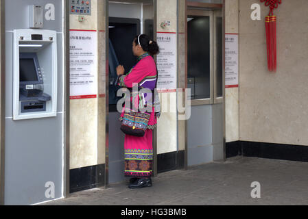 La Chine, le Yunnan, Shilin, femme portant le costume traditionnel Hani à ATM.. Banque D'Images