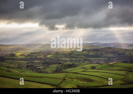 Rayons de soleil percent les nuages lourds, sur des collines vertes dans le haut du Peak District, Derbyshire, Angleterre. Banque D'Images