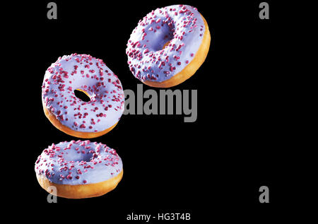 Trois donuts in motion isolated on black Banque D'Images