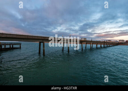 Jetée de Deal, dans le Kent en Angleterre. Jetée en béton construire dans les années 1950. Voir à partir de la fin de la jetée à la retour à la plage et de la ville. Dawn nuages sombres dans le ciel. Mer calme. Banque D'Images