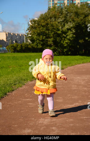 Petite fille en jaune vêtements sur une promenade dans le parc. Banque D'Images