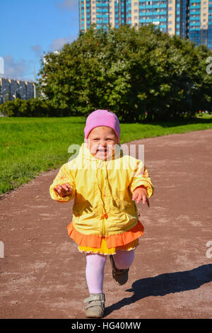 Petite fille en jaune vêtements sur une promenade dans le parc. Banque D'Images