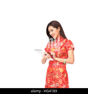 Belle fille asiatique en chinois qipao robe traditionnelle à l'aide de tablette numérique, le nouvel an chinois et de la technologie moderne concept, isolated on white zone Banque D'Images