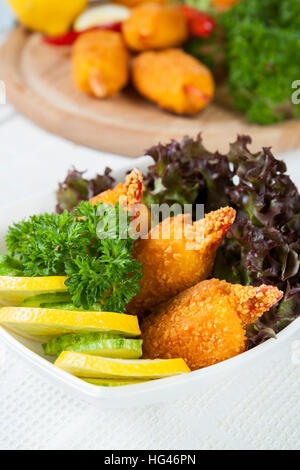 Pinces de crabe frit avec le concombre, le citron, la laitue et le persil on white plate Banque D'Images