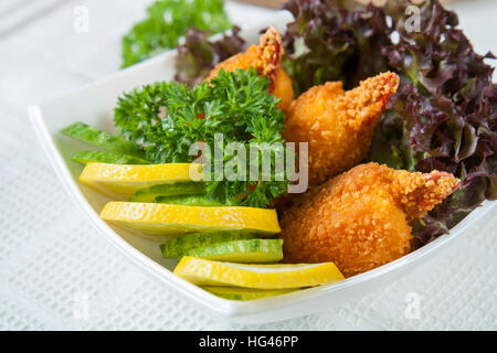 Pinces de crabe frit avec le concombre, le citron, la laitue et le persil on white plate Banque D'Images