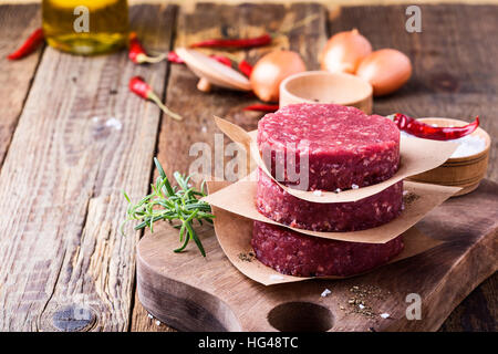 Le boeuf haché cru organique, pour faire des galettes rondes burger sur planche à découper en bois Banque D'Images