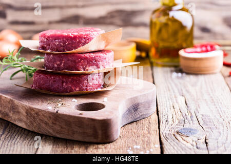 Le boeuf haché cru organique, pour faire des galettes rondes burger sur planche à découper en bois Banque D'Images