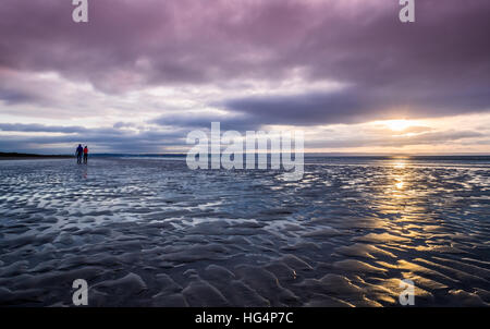 Un couple en train de marcher sur la plage le soir Banque D'Images