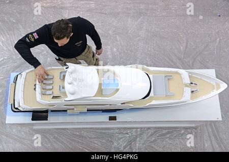 Un membre du personnel fait les derniers ajustements à un modèle de l'yacht Sunseeker 155', le plus grand bateau fabriqué par l'entreprise de Poole, l'avant du London Boat Show au centre ExCel de Londres. Banque D'Images