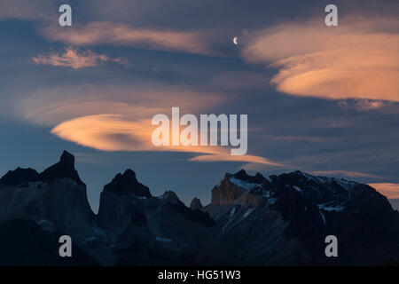 Nuages lenticulaires colorés et un croissant de lune au-dessus de sommets massif du Paine juste après le coucher du soleil. Les Cuernos del Paine, ou des cornes, sont sur la gauche wi Banque D'Images