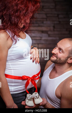 Happy pregnant woman and her husband holding baby shoes Banque D'Images