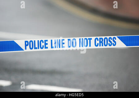 La scène de crime de la police est encerclée de l'autre côté d'une rue britannique, où l'on peut lire "police line do not cross". Banque D'Images