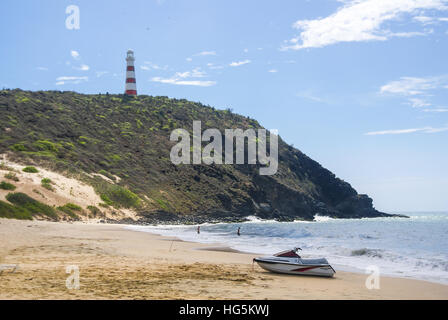 Une vue de loin d'un phare d'un sommet d'une colline dans une plage au milieu de la journée. Banque D'Images