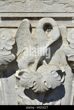Nettoyage d'oiseaux bec avec ses plumes . Un secours médiévale sur palais des Doges à Venise portique extérieur Banque D'Images