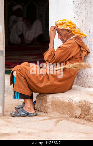 Elkhorbat, Maroc. L'homme se reposant à l'extérieur Entrée d'une mosquée. Banque D'Images