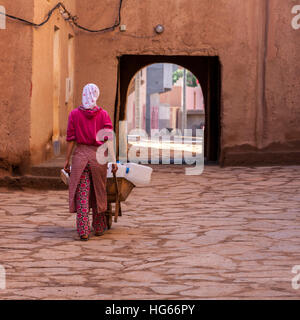 Ksar Elkhorbat, Maroc. Jeune femme prenant son eau pichets à la fonction d'un robinet d'eau à l'extérieur de la Casbah. Banque D'Images